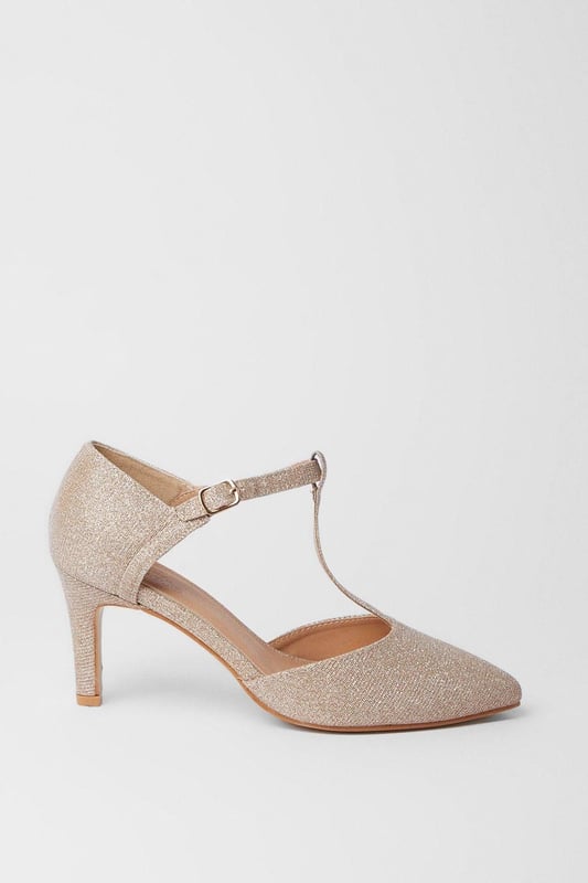 Elegant T-bar design with adjustable ankle strap for secure fit
        Pointed toe silhouette creates a flattering, elongated look
        Extra wide fit specially designed for enhanced comfort
        High heel measuring between 7-9cm adds sophisticated height
        Faux leather finish offers a polished, versatile appearance
    
    The Emma court shoes from Good For The Sole combine timeless style with exceptional comfort. Designed specifically with an extra wide fit, these pointed courts feature a classic T-bar strap that adds a touch of vintage charm while providing additional support. The high heel creates an elegant silhouette without compromising on wearability, making these courts perfect for daytime events where you want to make an impression. Style them with tailored trousers and a crisp blouse for family gatherings, or pair with a flowing midi skirt for casual lunches with friends. The neutral tone makes these courts incredibly versatile, allowing them to complement virtually any outfit in your wardrobe. The secure ankle strap ensures stability while the pointed toe design conveys sophistication, striking the perfect balance between fashion and function.
