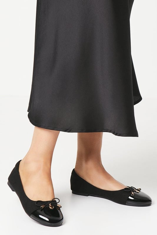 Elegant ballet pumps featuring a glossy toecap with decorative bow and charm detail
        Flat heel design measuring between 0-2cm for all-day comfort
        Soft faux leather construction with cushioned insole for enhanced wearability
        Part of the Good For the Sole collection, designed with comfort in mind
        Regular fit with rounded toe shape for a classic silhouette
    
    These charming Tash ballet pumps strike the perfect balance between professional polish and feminine style. The distinctive glossy toecap and delicate bow with metal charm detail add a touch of sophistication to this workplace essential. Pair with tailored trousers and a crisp blouse for office meetings, or team with a pencil skirt for a refined daytime look. The flat design ensures comfort throughout your busy day without compromising on style. For casual Fridays, these versatile pumps complement slim-fit jeans and a structured blazer beautifully. The cushioned insole provides welcome support during long days, making these ballet pumps an indispensable addition to your workwear wardrobe. Transition effortlessly from day to evening by swapping your work attire for a smart dress - these timeless flats will complement virtually any ensemble.