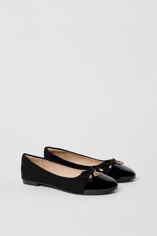 Elegant ballet pumps featuring a glossy toecap with decorative bow and charm detail
        Flat heel design measuring between 0-2cm for all-day comfort
        Soft faux leather construction with cushioned insole for enhanced wearability
        Part of the Good For the Sole collection, designed with comfort in mind
        Regular fit with rounded toe shape for a classic silhouette
    
    These charming Tash ballet pumps strike the perfect balance between professional polish and feminine style. The distinctive glossy toecap and delicate bow with metal charm detail add a touch of sophistication to this workplace essential. Pair with tailored trousers and a crisp blouse for office meetings, or team with a pencil skirt for a refined daytime look. The flat design ensures comfort throughout your busy day without compromising on style. For casual Fridays, these versatile pumps complement slim-fit jeans and a structured blazer beautifully. The cushioned insole provides welcome support during long days, making these ballet pumps an indispensable addition to your workwear wardrobe. Transition effortlessly from day to evening by swapping your work attire for a smart dress - these timeless flats will complement virtually any ensemble.
