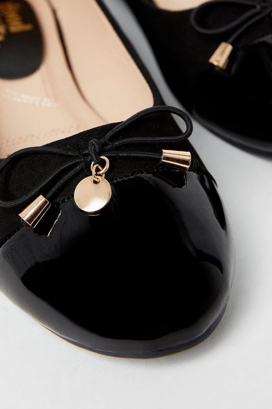 Elegant ballet pumps featuring a glossy toecap with decorative bow and charm detail
        Flat heel design measuring between 0-2cm for all-day comfort
        Soft faux leather construction with cushioned insole for enhanced wearability
        Part of the Good For the Sole collection, designed with comfort in mind
        Regular fit with rounded toe shape for a classic silhouette
    
    These charming Tash ballet pumps strike the perfect balance between professional polish and feminine style. The distinctive glossy toecap and delicate bow with metal charm detail add a touch of sophistication to this workplace essential. Pair with tailored trousers and a crisp blouse for office meetings, or team with a pencil skirt for a refined daytime look. The flat design ensures comfort throughout your busy day without compromising on style. For casual Fridays, these versatile pumps complement slim-fit jeans and a structured blazer beautifully. The cushioned insole provides welcome support during long days, making these ballet pumps an indispensable addition to your workwear wardrobe. Transition effortlessly from day to evening by swapping your work attire for a smart dress - these timeless flats will complement virtually any ensemble.