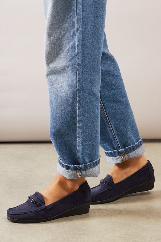 Faux suede moccasin loafers with decorative trim detail for a classic finish
        Subtle wedge heel (under 2cm) provides gentle lift without sacrificing comfort
        Cushioned footbed designed specifically for all-day wear
        Slip-on style with moccasin stitching for effortless everyday dressing
        Part of our Good For The Sole collection, crafted with comfort in mind
    
    These Viridiana moccasin loafers blend timeless style with exceptional comfort, making them a wardrobe essential for the modern woman. The subtle wedge provides just enough height to flatter without compromising on wearability, whilst the faux suede texture adds a touch of sophistication to casual ensembles. Style them with rolled-up jeans for a relaxed weekend look, or pair with tailored trousers and a crisp shirt for smart-casual office days. The versatile design works beautifully with everything from floaty midi dresses to cropped trousers, making these loafers perfect for family gatherings, casual brunches, or those busy days when you're on your feet. The thoughtful comfort features ensure these will quickly become your go-to footwear choice when you need both style and practicality.