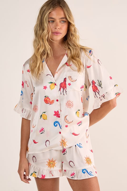 Luxurious satin finish with playful western-inspired conversational print featuring fruits, suns, and desert motifs
        Relaxed button-up short sleeve top with charming ruffle trim detailing
        Matching shorts with ruffle hem for a coordinated nightwear look
        Comfortable loose fit designed for ease of movement during sleep
        Collared neckline with classic front button closure for adjustable styling
    
    Drift into dreamland with this delightfully whimsical Satin Western Conversational Ruffle Pajama Shorts Set from Nasty Gal. The charming print showcases a playful array of western-inspired motifs, creating a fun yet sophisticated nightwear option. The relaxed silhouette features a button-up top with short sleeves and a classic collar, whilst the coordinating shorts offer the perfect balance of comfort and style. The ruffle detailing adds a feminine touch to this set, making bedtime feel that little bit more special. Perfect for warm summer evenings or cosy nights in, this set can be worn whilst lounging with a good book and a cup of tea, or for those lazy weekend mornings when breakfast in bed is calling. For chillier nights, simply pair with fluffy socks and a lightweight dressing gown for additional warmth without compromising on style.