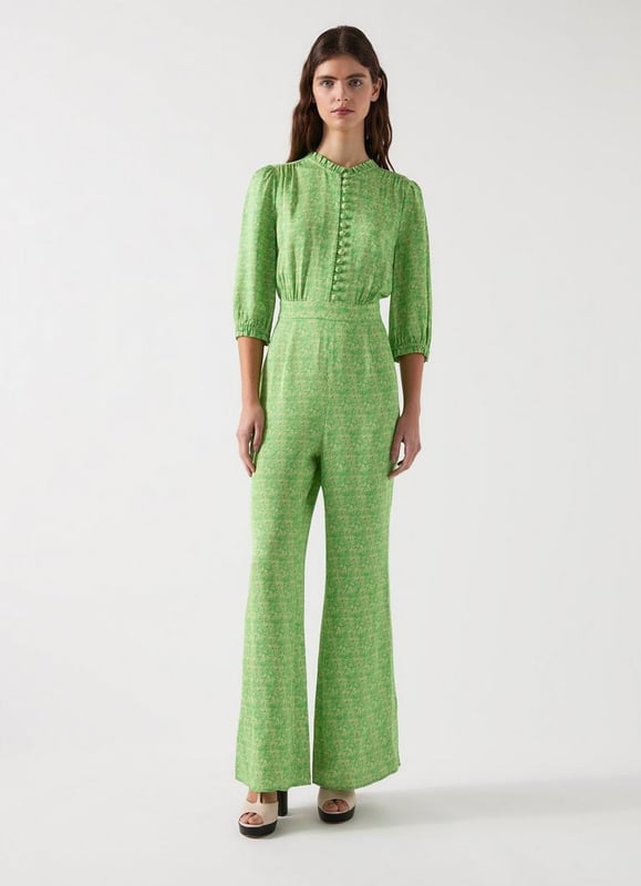 The Naomi jumpsuit features swirling abstract prints on a green satin crepe canvas. This  design includes neck and cuff frills, complemented by ball self-covered buttons with rouleau loops, made from viscose. Ideal for glamorous evenings, pair it with sleek heels and statement earrings for an unforgettable look.