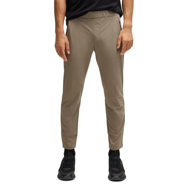 Mens BOSS T Basin Tapered-leg trousers in water-repellent stretch fabric in beigeThese BOSS Menswear tapered-fit trousers have adjustability at the waist and hems. Expand your wardrobe with this versatile pair crafted in stretch material with water repellency.- Elasticated waistband with inner drawcord- Zipped front pockets- Tapered leg- Snap buttons on hem- Technical 4-way stretch for maximum freedom of movement- Quick-dry  water-repellent and easy iron.- Main material: 90% Polyamide  10% Elastane.  Pocketing: 100% Polyester.  Machine washable.- Ref: 50529668-334
