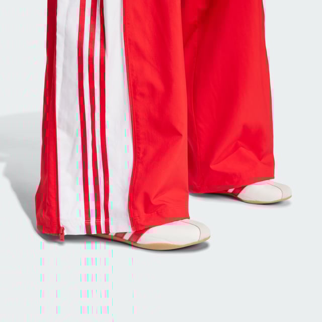 The 3-Stripes on these adidas pants have two purposes — celebrate their adidas DNA boldly, and to emphasise the wide leg silhouette. The flowing look can be adjusted at the cuffs, with a pearl at the stopper of the bungees for added decadence. A two-way zip on the side allows you to play with the aesthetic even further, by creating more of a balloon shape with the volume.This product is made with 100% recycled materials. By reusing materials that have already been created, adidas help to reduce waste and our reliance on finite resources and reduce the footprint of the products adidas make.  - Loose fit - Drawcord on elastic waist - 100% polyester (recycled) - Side pockets - Bungee-adjustable hems  Shipped by adidas