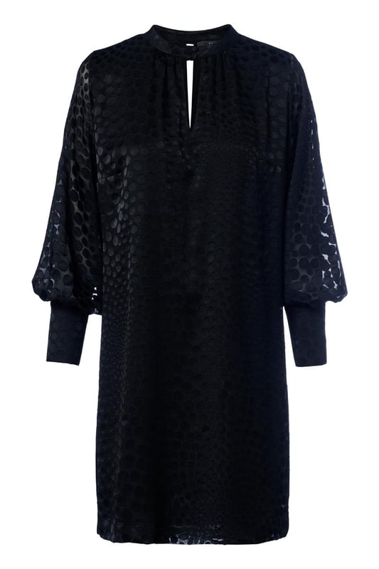 Wählen Sie diese Saison das Abilene-Kleid in klassischem Schwarz. Dieses stilvolle Kleid vereint mühelos Eleganz und Komfort mit einem wunderschönen glänzenden Polka-Dot-Motiv auf einem halbtransparenten Stoff. Das Design verfügt über einen Stehkragen und dezente Schlüssellochöffnungen vorne und hinten, die für einen raffinierten und einzigartigen Look sorgen. Die langen Ballonärmel und breiten Bündchen sorgen für einen modischen Touch, während die knielange und lockere Passform ein angenehmes Tragegefühl garantiert. Das glänzende Polka-Dot-Motiv verleiht dem Kleid einen luxuriösen Designer-Look und macht es zu einem echten Hingucker. Kombinieren Sie das Kleid tagsüber mit robusten Stiefeln und einer Jeansjacke für ein lässig-schickes Outfit oder tragen Sie es abends mit eleganten Heels für ein sommerliches Dinner-Date oder einen schönen Abenddrink. Mit einem Gürtel können Sie eine schmeichelnde Sanduhrfigur kreieren, das Kleid kann aber auch bequem locker getragen werden. Fashion-Tipp: Entdecken Sie auch die grüne Variante dieses Kleides oder entscheiden Sie sich für die stylische schwarze Bluse mit dem gleichen verspielten Polka-Dot-Motiv!