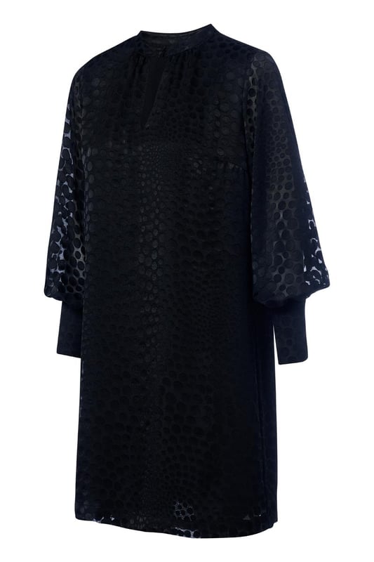 Wählen Sie diese Saison das Abilene-Kleid in klassischem Schwarz. Dieses stilvolle Kleid vereint mühelos Eleganz und Komfort mit einem wunderschönen glänzenden Polka-Dot-Motiv auf einem halbtransparenten Stoff. Das Design verfügt über einen Stehkragen und dezente Schlüssellochöffnungen vorne und hinten, die für einen raffinierten und einzigartigen Look sorgen. Die langen Ballonärmel und breiten Bündchen sorgen für einen modischen Touch, während die knielange und lockere Passform ein angenehmes Tragegefühl garantiert. Das glänzende Polka-Dot-Motiv verleiht dem Kleid einen luxuriösen Designer-Look und macht es zu einem echten Hingucker. Kombinieren Sie das Kleid tagsüber mit robusten Stiefeln und einer Jeansjacke für ein lässig-schickes Outfit oder tragen Sie es abends mit eleganten Heels für ein sommerliches Dinner-Date oder einen schönen Abenddrink. Mit einem Gürtel können Sie eine schmeichelnde Sanduhrfigur kreieren, das Kleid kann aber auch bequem locker getragen werden. Fashion-Tipp: Entdecken Sie auch die grüne Variante dieses Kleides oder entscheiden Sie sich für die stylische schwarze Bluse mit dem gleichen verspielten Polka-Dot-Motiv!
