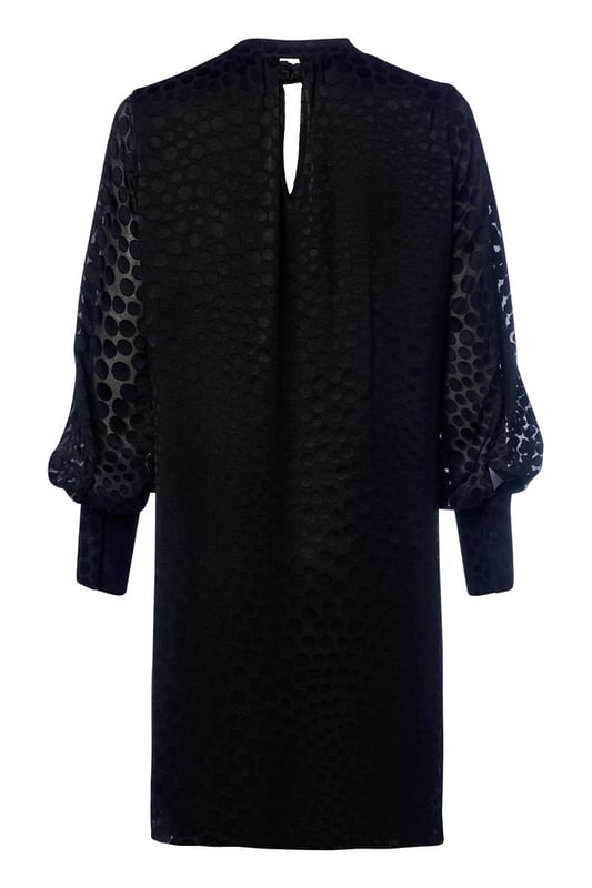 Wählen Sie diese Saison das Abilene-Kleid in klassischem Schwarz. Dieses stilvolle Kleid vereint mühelos Eleganz und Komfort mit einem wunderschönen glänzenden Polka-Dot-Motiv auf einem halbtransparenten Stoff. Das Design verfügt über einen Stehkragen und dezente Schlüssellochöffnungen vorne und hinten, die für einen raffinierten und einzigartigen Look sorgen. Die langen Ballonärmel und breiten Bündchen sorgen für einen modischen Touch, während die knielange und lockere Passform ein angenehmes Tragegefühl garantiert. Das glänzende Polka-Dot-Motiv verleiht dem Kleid einen luxuriösen Designer-Look und macht es zu einem echten Hingucker. Kombinieren Sie das Kleid tagsüber mit robusten Stiefeln und einer Jeansjacke für ein lässig-schickes Outfit oder tragen Sie es abends mit eleganten Heels für ein sommerliches Dinner-Date oder einen schönen Abenddrink. Mit einem Gürtel können Sie eine schmeichelnde Sanduhrfigur kreieren, das Kleid kann aber auch bequem locker getragen werden. Fashion-Tipp: Entdecken Sie auch die grüne Variante dieses Kleides oder entscheiden Sie sich für die stylische schwarze Bluse mit dem gleichen verspielten Polka-Dot-Motiv!