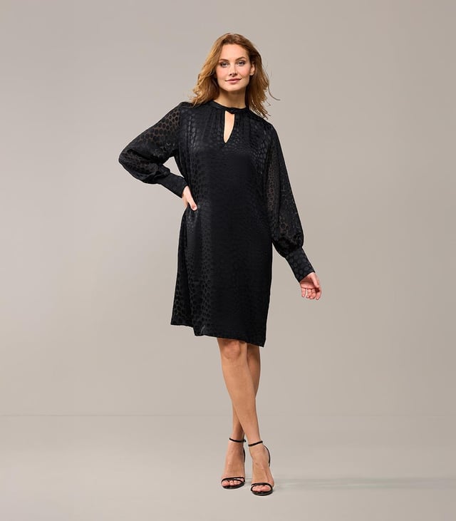Wählen Sie diese Saison das Abilene-Kleid in klassischem Schwarz. Dieses stilvolle Kleid vereint mühelos Eleganz und Komfort mit einem wunderschönen glänzenden Polka-Dot-Motiv auf einem halbtransparenten Stoff. Das Design verfügt über einen Stehkragen und dezente Schlüssellochöffnungen vorne und hinten, die für einen raffinierten und einzigartigen Look sorgen. Die langen Ballonärmel und breiten Bündchen sorgen für einen modischen Touch, während die knielange und lockere Passform ein angenehmes Tragegefühl garantiert. Das glänzende Polka-Dot-Motiv verleiht dem Kleid einen luxuriösen Designer-Look und macht es zu einem echten Hingucker. Kombinieren Sie das Kleid tagsüber mit robusten Stiefeln und einer Jeansjacke für ein lässig-schickes Outfit oder tragen Sie es abends mit eleganten Heels für ein sommerliches Dinner-Date oder einen schönen Abenddrink. Mit einem Gürtel können Sie eine schmeichelnde Sanduhrfigur kreieren, das Kleid kann aber auch bequem locker getragen werden. Fashion-Tipp: Entdecken Sie auch die grüne Variante dieses Kleides oder entscheiden Sie sich für die stylische schwarze Bluse mit dem gleichen verspielten Polka-Dot-Motiv!