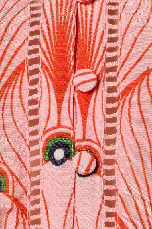 De elegante Belfast print tuniek uit de nieuwste collectie van Caroline Tensen is dé ideale keuze voor de zomer. De soepelvallende, wijde pasvorm en verfijnde details geven de tuniek zowel een chique als een ontspannen uitstraling. Het opvallende oranje pauwenprint op een zachte koraalroze achtergrond maakt deze lange tuniek bijzonder uniek. De lange mouwen hebben een subtiel ballon-effect en eindigen in speelse ruches bij de polsen, afgewerkt met elastiek voor extra comfort. De tuniek heeft een V-hals met een opengewerkte bies en een recht silhouet, waardoor hij heerlijk comfortabel zit. Dankzij het vaste strikceintuur kun je de taille mooi benadrukk