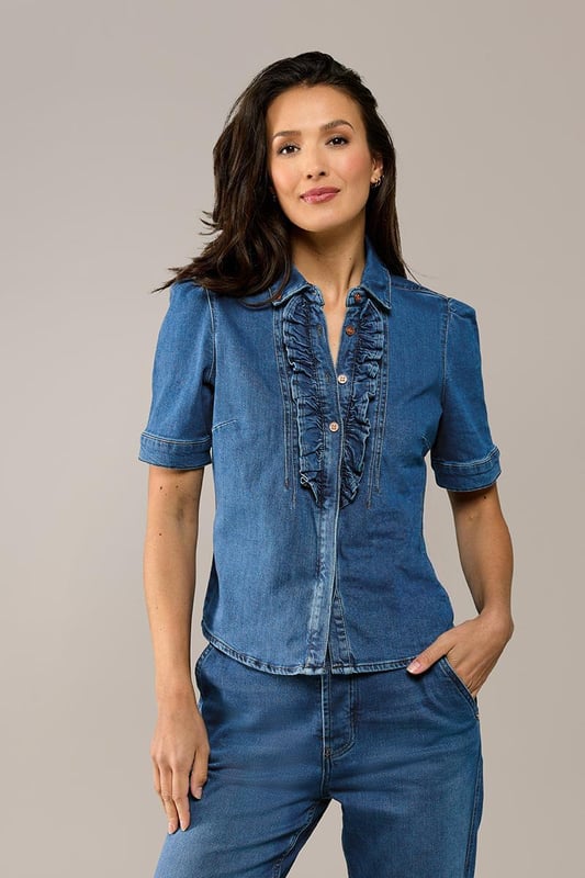 Entscheiden Sie sich diesen Sommer für eine trendige Bluse im Denim-Look! Dieses stylische Stück aus meiner neusten Kollektion ist die perfekte Grundlage für jedes Outfit. Die Bluse in Mittelblau hat kurze Puffärmel und einen eleganten hohen Kragen. Der Knopfverschluss in der Mitte ist mit einer verspielten Rüsche versehen, die für einen charmanten Twist sorgt. Dank der taillierten Passform und der Hüftlänge betont die Bluse Ihre Silhouette auf schmeichelhafte Weise. Diese sommerliche Bluse aus Bio-Baumwolle bietet nicht nur Stil, sondern auch höchsten Tragekomfort. Der Stretch-Denim passt sich wunderbar Ihrem Körper an und betont Ihre weiblichen Kurven. Entdecken Sie auch die Jeansbluse Brighton in Weiß und Hellblau!