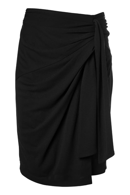 De elegante zwarte Riley rok is zowel casual als sportief en is een must-have in je garderobe. Deze rok heeft een mooie lengte die net boven de knie valt en is gemaakt van een hoogwaardige jersey stof die ultiem comfort biedt. De fijne stretch in de stof zorgt ervoor dat de rok soepel om je lichaam valt, waardoor je hem niet wilt uittrekken. Het asymmetrische strikdetail aan de linkerzijde van de overslagrok geeft een uniek en stijlvol effect. De rok heeft een rechte pasvorm en is voorzien van een elastisch detail in de tailleband aan de achterkant voor optimaal draagcomfort. Het rechte model staat garant voor een perfecte pasvorm en maximale draagbaarheid. Combineer de stijlvolle Riley overslagrok met de zwarte Raisy top voor een speelse jurk-look, of draag hem met een blazer en laarsjes voor een chique, afgewerkte look. Je kunt de zwarte rok ook combineren met een mooie blouse en een laars voor een elegante kantooroutfit. Ga voor een look die zowel comfortabel als chic is!