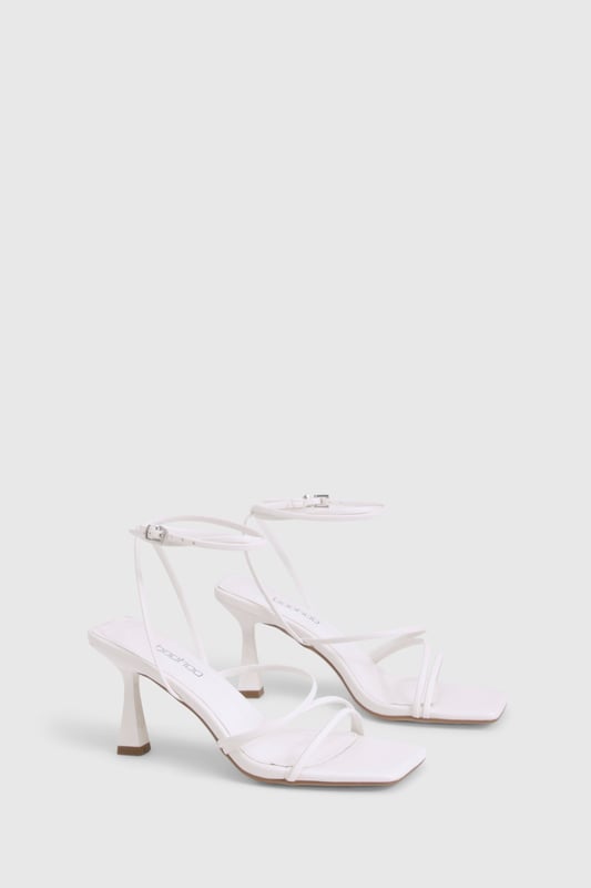 Delicate strappy design with minimalist aesthetic for versatile styling
        Square toe silhouette for a contemporary, fashion-forward look
        Comfortable mid-height heel measuring between 2.5-4.5cm
        Adjustable ankle strap with buckle fastening for secure fit
        Wide fit design offering extra room for all-night comfort
    
    These strappy mid-height heels strike the perfect balance between style and comfort, making them an essential addition to your night-out wardrobe. The elegant thin straps create a flattering effect on the foot whilst the square toe adds a modern twist to this classic silhouette. Designed with comfort in mind, the wide fit construction provides extra room where you need it most, whilst the modest heel height ensures you can dance from dusk till dawn without compromise. Style these versatile heels with a mini dress for drinks with the girls, or pair with tailored trousers and a statement top for more sophisticated evening affairs. The neutral design makes these heels incredibly adaptable, working seamlessly with both bold patterns and monochrome outfits alike. A true wardrobe hero that will see you through countless social occasions with effortless style.