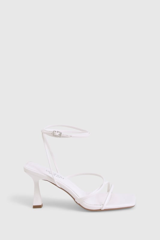 Delicate strappy design with minimalist aesthetic for versatile styling
        Square toe silhouette for a contemporary, fashion-forward look
        Comfortable mid-height heel measuring between 2.5-4.5cm
        Adjustable ankle strap with buckle fastening for secure fit
        Wide fit design offering extra room for all-night comfort
    
    These strappy mid-height heels strike the perfect balance between style and comfort, making them an essential addition to your night-out wardrobe. The elegant thin straps create a flattering effect on the foot whilst the square toe adds a modern twist to this classic silhouette. Designed with comfort in mind, the wide fit construction provides extra room where you need it most, whilst the modest heel height ensures you can dance from dusk till dawn without compromise. Style these versatile heels with a mini dress for drinks with the girls, or pair with tailored trousers and a statement top for more sophisticated evening affairs. The neutral design makes these heels incredibly adaptable, working seamlessly with both bold patterns and monochrome outfits alike. A true wardrobe hero that will see you through countless social occasions with effortless style.