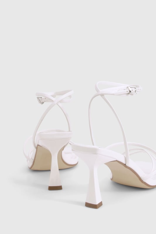 Delicate strappy design with minimalist aesthetic for versatile styling
        Square toe silhouette for a contemporary, fashion-forward look
        Comfortable mid-height heel measuring between 2.5-4.5cm
        Adjustable ankle strap with buckle fastening for secure fit
        Wide fit design offering extra room for all-night comfort
    
    These strappy mid-height heels strike the perfect balance between style and comfort, making them an essential addition to your night-out wardrobe. The elegant thin straps create a flattering effect on the foot whilst the square toe adds a modern twist to this classic silhouette. Designed with comfort in mind, the wide fit construction provides extra room where you need it most, whilst the modest heel height ensures you can dance from dusk till dawn without compromise. Style these versatile heels with a mini dress for drinks with the girls, or pair with tailored trousers and a statement top for more sophisticated evening affairs. The neutral design makes these heels incredibly adaptable, working seamlessly with both bold patterns and monochrome outfits alike. A true wardrobe hero that will see you through countless social occasions with effortless style.