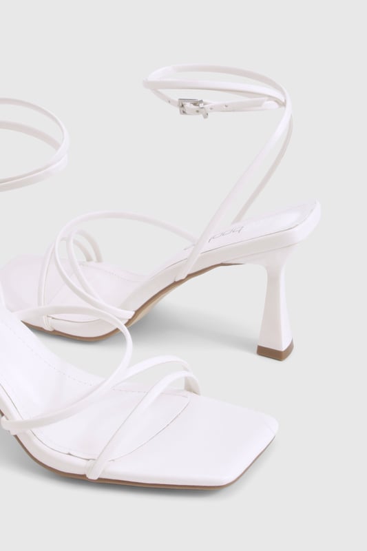 Delicate strappy design with minimalist aesthetic for versatile styling
        Square toe silhouette for a contemporary, fashion-forward look
        Comfortable mid-height heel measuring between 2.5-4.5cm
        Adjustable ankle strap with buckle fastening for secure fit
        Wide fit design offering extra room for all-night comfort
    
    These strappy mid-height heels strike the perfect balance between style and comfort, making them an essential addition to your night-out wardrobe. The elegant thin straps create a flattering effect on the foot whilst the square toe adds a modern twist to this classic silhouette. Designed with comfort in mind, the wide fit construction provides extra room where you need it most, whilst the modest heel height ensures you can dance from dusk till dawn without compromise. Style these versatile heels with a mini dress for drinks with the girls, or pair with tailored trousers and a statement top for more sophisticated evening affairs. The neutral design makes these heels incredibly adaptable, working seamlessly with both bold patterns and monochrome outfits alike. A true wardrobe hero that will see you through countless social occasions with effortless style.