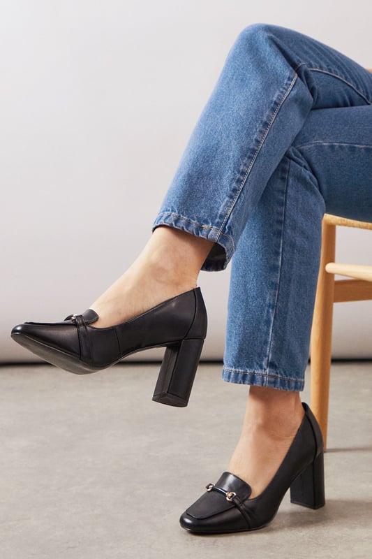 Sophisticated loafer design with decorative metal bar detail across the front
        Generous wide fit for all-day comfort in the office
        Sturdy high block heel measuring between 7-9cm for elegant height
        Smooth faux leather finish that pairs beautifully with workwear
        Classic square toe silhouette offering timeless appeal and extra room
    
    These Lucky High Block Heeled Loafers from Wallis strike the perfect balance between sophistication and practicality for the modern professional. The generous wide fit ensures comfort throughout your busy workday, whilst the substantial block heel provides stability without sacrificing style. Pair these versatile loafers with tailored trousers as shown for a polished office ensemble, or style with a pencil skirt and crisp blouse for important meetings. The sleek design transitions effortlessly from day to evening, making them ideal for after-work gatherings. The decorative metal bar adds just the right touch of glamour to complement your most refined outfits, whilst the square toe offers contemporary flair. These loafers will quickly become your go-to footwear choice when you need to project confidence and sophistication in the workplace.