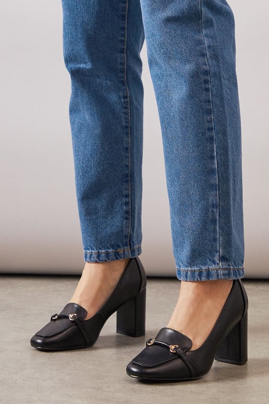 Sophisticated loafer design with decorative metal bar detail across the front
        Generous wide fit for all-day comfort in the office
        Sturdy high block heel measuring between 7-9cm for elegant height
        Smooth faux leather finish that pairs beautifully with workwear
        Classic square toe silhouette offering timeless appeal and extra room
    
    These Lucky High Block Heeled Loafers from Wallis strike the perfect balance between sophistication and practicality for the modern professional. The generous wide fit ensures comfort throughout your busy workday, whilst the substantial block heel provides stability without sacrificing style. Pair these versatile loafers with tailored trousers as shown for a polished office ensemble, or style with a pencil skirt and crisp blouse for important meetings. The sleek design transitions effortlessly from day to evening, making them ideal for after-work gatherings. The decorative metal bar adds just the right touch of glamour to complement your most refined outfits, whilst the square toe offers contemporary flair. These loafers will quickly become your go-to footwear choice when you need to project confidence and sophistication in the workplace.