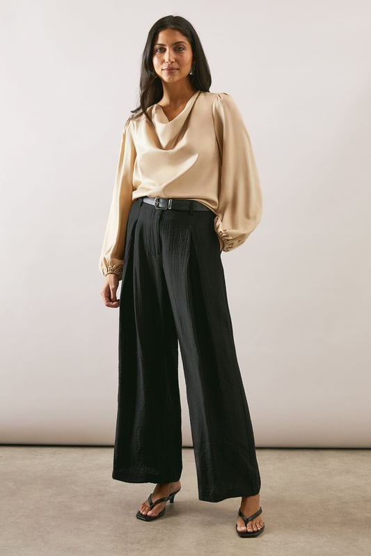 Elegant cowl neckline that drapes beautifully for a sophisticated silhouette
        Statement balloon sleeves with delicate gathered cuffs for a touch of drama
        Lustrous satin finish that catches the light with subtle sheen
        Versatile loose fit that flatters all body types
        Clean-lined design with a smooth back for effortless styling
    
    This Wallis satin blouse combines timeless elegance with contemporary styling. The graceful cowl neckline creates a flattering drape that frames your dcolletage beautifully, whilst the voluminous balloon sleeves add a touch of refined drama to your ensemble. Style as seen with wide-leg trousers and a slim belt for a balanced silhouette that works wonderfully for family gatherings or lunch with friends. The fluid fabric moves gracefully with you, making this piece ideal for daytime events where comfort and style are equally important. Pair with tailored trousers and flats for work, or dress down with your favourite denim and trainers for weekend brunches. This versatile blouse transitions effortlessly from day to evening, making it a wardrobe essential for the modern woman who values both sophistication and comfort.