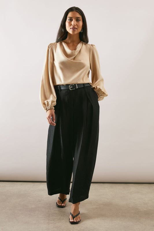 Elegant cowl neckline that drapes beautifully for a sophisticated silhouette
        Statement balloon sleeves with delicate gathered cuffs for a touch of drama
        Lustrous satin finish that catches the light with subtle sheen
        Versatile loose fit that flatters all body types
        Clean-lined design with a smooth back for effortless styling
    
    This Wallis satin blouse combines timeless elegance with contemporary styling. The graceful cowl neckline creates a flattering drape that frames your dcolletage beautifully, whilst the voluminous balloon sleeves add a touch of refined drama to your ensemble. Style as seen with wide-leg trousers and a slim belt for a balanced silhouette that works wonderfully for family gatherings or lunch with friends. The fluid fabric moves gracefully with you, making this piece ideal for daytime events where comfort and style are equally important. Pair with tailored trousers and flats for work, or dress down with your favourite denim and trainers for weekend brunches. This versatile blouse transitions effortlessly from day to evening, making it a wardrobe essential for the modern woman who values both sophistication and comfort.