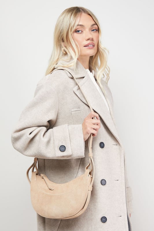 Distinctive half-moon silhouette for a contemporary aesthetic
        Soft faux suede texture adds a luxurious touch to casual outfits
        Adjustable crossbody strap for comfortable all-day wear
        Secure zip-top closure to keep essentials safe
        Compact yet spacious enough for daily necessities
    
    The Relly Faux Suede Half Moon Crossbody Bag combines practicality with feminine charm, embodying Oasis's signature style. The curved silhouette creates a soft, modern look that pairs beautifully with both casual and smart-casual ensembles. Style with relaxed denim and a floaty blouse for daytime outings, or match with a floral day dress for garden parties and family gatherings. The versatile design makes it perfect for weekend shopping trips, coffee dates, or casual lunches. The adjustable strap allows for customised wear, while the interior provides just enough room for your phone, wallet, keys and lipstick. This bag effortlessly transitions from day to evening, making it an essential addition to your accessory collection for those moments when you want to travel light without compromising on style.