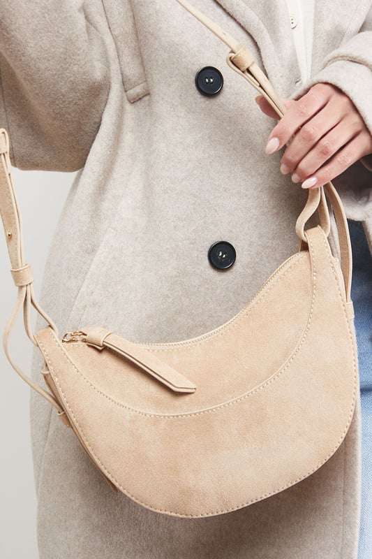 Distinctive half-moon silhouette for a contemporary aesthetic
        Soft faux suede texture adds a luxurious touch to casual outfits
        Adjustable crossbody strap for comfortable all-day wear
        Secure zip-top closure to keep essentials safe
        Compact yet spacious enough for daily necessities
    
    The Relly Faux Suede Half Moon Crossbody Bag combines practicality with feminine charm, embodying Oasis's signature style. The curved silhouette creates a soft, modern look that pairs beautifully with both casual and smart-casual ensembles. Style with relaxed denim and a floaty blouse for daytime outings, or match with a floral day dress for garden parties and family gatherings. The versatile design makes it perfect for weekend shopping trips, coffee dates, or casual lunches. The adjustable strap allows for customised wear, while the interior provides just enough room for your phone, wallet, keys and lipstick. This bag effortlessly transitions from day to evening, making it an essential addition to your accessory collection for those moments when you want to travel light without compromising on style.