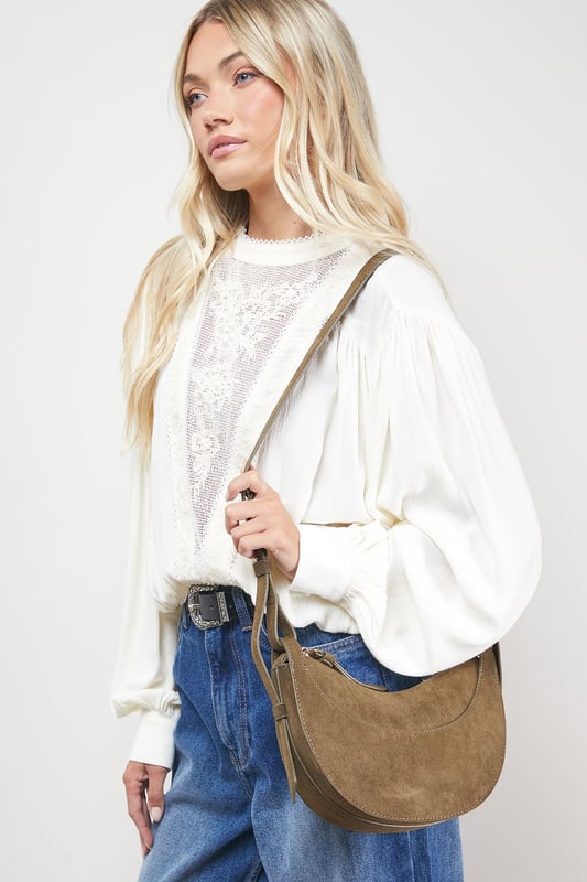 Distinctive half-moon silhouette for a contemporary aesthetic
        Soft faux suede texture adds a luxurious touch to casual outfits
        Adjustable crossbody strap for comfortable all-day wear
        Secure zip-top closure to keep essentials safe
        Compact yet spacious enough for daily necessities
    
    The Relly Faux Suede Half Moon Crossbody Bag combines practicality with feminine charm, embodying Oasis's signature style. The curved silhouette creates a soft, modern look that pairs beautifully with both casual and smart-casual ensembles. Style with relaxed denim and a floaty blouse for daytime outings, or match with a floral day dress for garden parties and family gatherings. The versatile design makes it perfect for weekend shopping trips, coffee dates, or casual lunches. The adjustable strap allows for customised wear, while the interior provides just enough room for your phone, wallet, keys and lipstick. This bag effortlessly transitions from day to evening, making it an essential addition to your accessory collection for those moments when you want to travel light without compromising on style.
