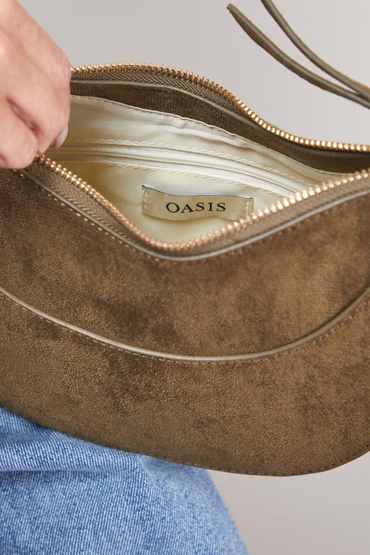 Distinctive half-moon silhouette for a contemporary aesthetic
        Soft faux suede texture adds a luxurious touch to casual outfits
        Adjustable crossbody strap for comfortable all-day wear
        Secure zip-top closure to keep essentials safe
        Compact yet spacious enough for daily necessities
    
    The Relly Faux Suede Half Moon Crossbody Bag combines practicality with feminine charm, embodying Oasis's signature style. The curved silhouette creates a soft, modern look that pairs beautifully with both casual and smart-casual ensembles. Style with relaxed denim and a floaty blouse for daytime outings, or match with a floral day dress for garden parties and family gatherings. The versatile design makes it perfect for weekend shopping trips, coffee dates, or casual lunches. The adjustable strap allows for customised wear, while the interior provides just enough room for your phone, wallet, keys and lipstick. This bag effortlessly transitions from day to evening, making it an essential addition to your accessory collection for those moments when you want to travel light without compromising on style.