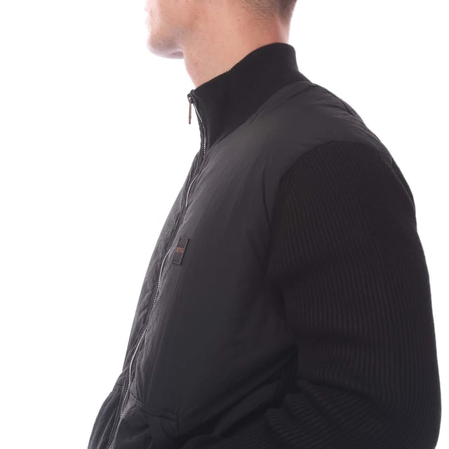 Mens Hugo Boss Kydalnrio Hybrid Jacket in black.- Funnel neck.- Full zip fastening.- Two front pockets.- Ribbed cuffs and hem.- Nylon front.- Square Boss badge on the chest.- Knitted.- 40% Acrylic  39% Virgin Wool  18% Polyamide  3% Elastane.- Ref: 50531494001