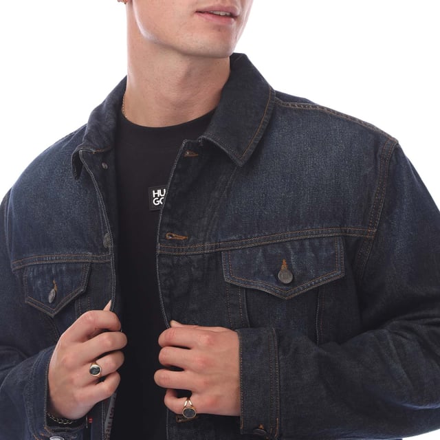 Make a versatile addition to your casual wardrobe with this jacket by HUGO Menswear. Crafted in dark-blue raw denim. Hem adjusters  signature trims. This product’s raw material is derived from regenerative agriculture: an approach focused on preservation and restoration that aims to increase biodiversity  preserve water quality and improve soil health while absorbing CO2. Regenerative agriculture also promotes animal welfare and fair working conditions for farmers.- 80% Cotton  20% Cotton (Recycled).- Ref: 50530639405