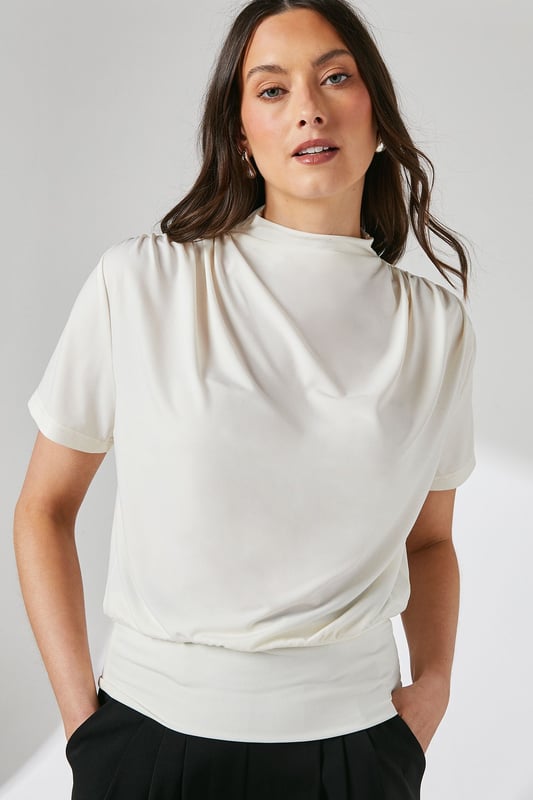 Elegant high neck design with sophisticated drape detail across the front
        Short sleeves with subtle gathering at the shoulders for added dimension
        Fitted ribbed hem creates a flattering silhouette
        Delicate keyhole fastening at the back for refined finishing
        Soft jersey fabric with gentle stretch for all-day comfort
    
    This versatile Principles top combines contemporary styling with everyday comfort. The graceful drape detail adds visual interest to the high neckline, whilst the fitted hem creates a polished, tucked-in appearance without the fuss. Perfect for daytime engagements, style with wide-leg trousers as shown for a balanced silhouette that works beautifully for family gatherings or weekend brunches. Alternatively, pair with tailored cigarette trousers and ballet flats for a smart-casual office look. The jersey fabric offers just the right amount of stretch to maintain its shape throughout the day, making this an ideal piece for your capsule wardrobe. Accessorise with statement earrings to draw attention to the elegant neckline and complete your effortlessly chic ensemble.