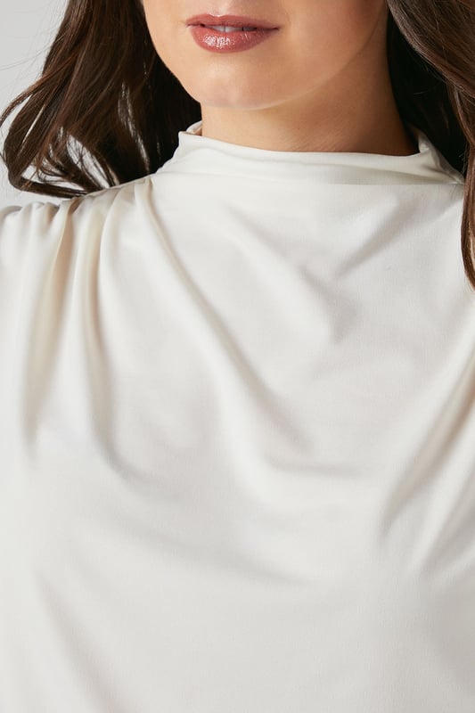 Elegant high neck design with sophisticated drape detail across the front
        Short sleeves with subtle gathering at the shoulders for added dimension
        Fitted ribbed hem creates a flattering silhouette
        Delicate keyhole fastening at the back for refined finishing
        Soft jersey fabric with gentle stretch for all-day comfort
    
    This versatile Principles top combines contemporary styling with everyday comfort. The graceful drape detail adds visual interest to the high neckline, whilst the fitted hem creates a polished, tucked-in appearance without the fuss. Perfect for daytime engagements, style with wide-leg trousers as shown for a balanced silhouette that works beautifully for family gatherings or weekend brunches. Alternatively, pair with tailored cigarette trousers and ballet flats for a smart-casual office look. The jersey fabric offers just the right amount of stretch to maintain its shape throughout the day, making this an ideal piece for your capsule wardrobe. Accessorise with statement earrings to draw attention to the elegant neckline and complete your effortlessly chic ensemble.