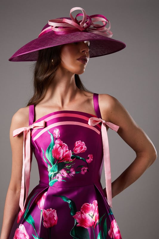 Dramatic wide brim design for maximum impact at special occasions
        Statement bow loop detail adds a touch of artistic flair
        Crafted from natural Abaca fabric with a textured finish
        Versatile one-size design suitable for various hairstyles
        Lightweight construction ensures comfortable wear throughout the day
    
    Make a sophisticated entrance at your next special event with this stunning wide brim hat. The Lisa Tan Bow Loop design showcases exceptional craftsmanship with its sculptural silhouette and artfully arranged bow detail that creates visual interest from every angle. Perfect for weddings, race days and garden parties, this hat pairs beautifully with fitted dresses or tailored ensembles as shown by our model. The natural Abaca construction offers a refined texture that complements formal attire whilst maintaining a contemporary edge. Style with an elegant updo to showcase the hat's dramatic proportions, or wear with loose waves for a more relaxed interpretation. Complete your look with statement earrings and a clutch bag in complementary tones for a cohesive ensemble that reflects true British occasion dressing.