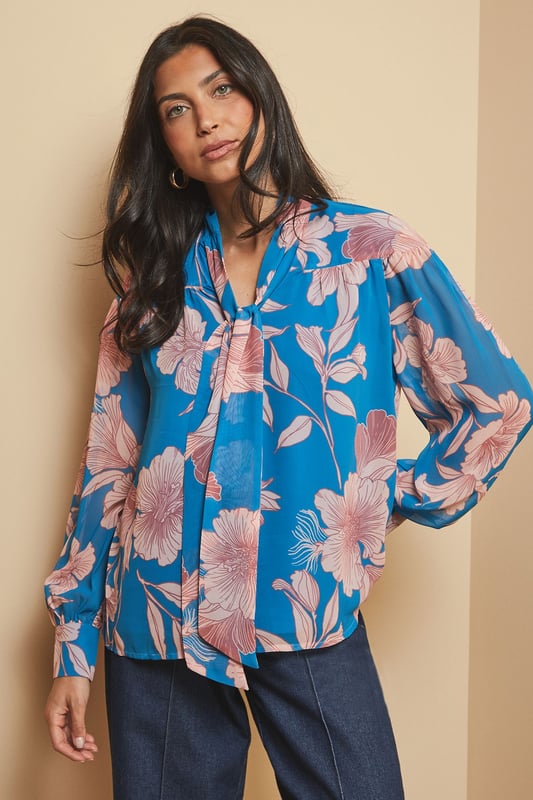Elegant tie neck detail creates a sophisticated silhouette
        Striking floral print adds visual interest to your daywear collection
        V-neckline frames the face beautifully
        Long sleeves with subtle gathering for a feminine touch
        Regular fit ensures comfortable all-day wear
    
    This captivating floral print blouse from Wallis combines effortless style with versatility. The elegant tie neck detail allows you to customise your look-wear it loosely draped for casual gatherings or neatly tied for a more polished appearance. Style with wide-leg denim trousers as shown for a contemporary daytime ensemble, perfect for lunch with friends or weekend shopping trips. The lightweight woven fabric drapes beautifully, creating movement as you walk. For cooler days, layer under a tailored blazer or casual cardigan. Complete your look with hoop earrings and ankle boots for an outfit that transitions seamlessly from family brunches to informal dinner dates. This blouse offers the perfect balance of comfort and sophistication for the woman who appreciates glamour in her everyday wardrobe.