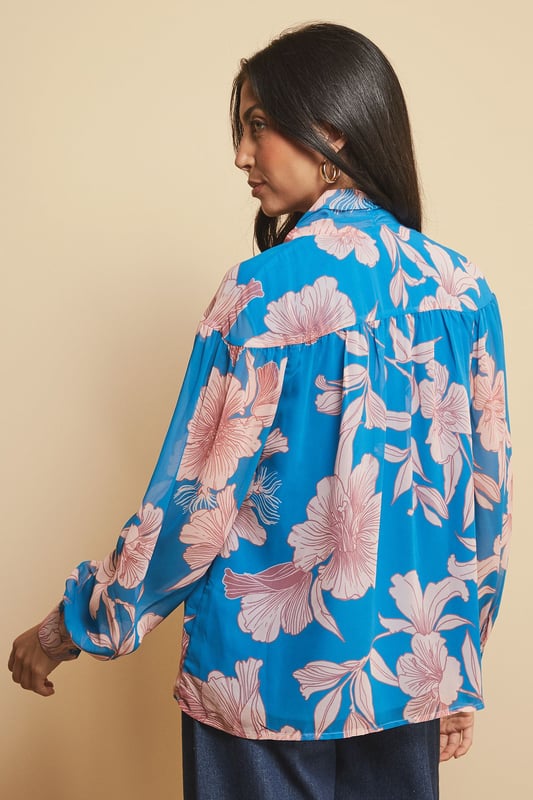 Elegant tie neck detail creates a sophisticated silhouette
        Striking floral print adds visual interest to your daywear collection
        V-neckline frames the face beautifully
        Long sleeves with subtle gathering for a feminine touch
        Regular fit ensures comfortable all-day wear
    
    This captivating floral print blouse from Wallis combines effortless style with versatility. The elegant tie neck detail allows you to customise your look-wear it loosely draped for casual gatherings or neatly tied for a more polished appearance. Style with wide-leg denim trousers as shown for a contemporary daytime ensemble, perfect for lunch with friends or weekend shopping trips. The lightweight woven fabric drapes beautifully, creating movement as you walk. For cooler days, layer under a tailored blazer or casual cardigan. Complete your look with hoop earrings and ankle boots for an outfit that transitions seamlessly from family brunches to informal dinner dates. This blouse offers the perfect balance of comfort and sophistication for the woman who appreciates glamour in her everyday wardrobe.