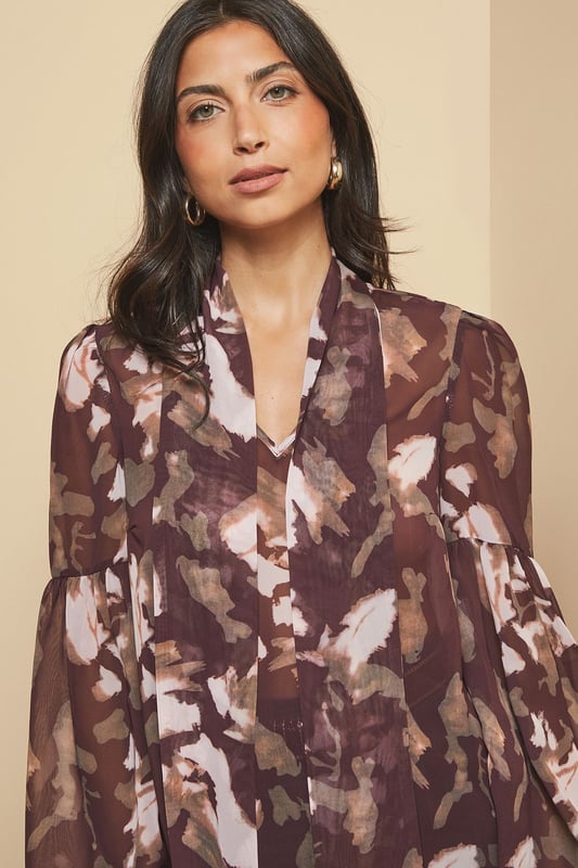 Elegant tie neck detail creates a sophisticated silhouette
        Dramatic balloon sleeves add a contemporary touch to this classic blouse
        Lightweight woven fabric ensures comfort throughout the day
        Versatile high neckline offers modest yet stylish coverage
        Flattering loose fit drapes beautifully for effortless wear
    
    This captivating floral blouse from Wallis combines timeless elegance with modern design elements. The statement tie neck and voluminous sleeves create a balanced silhouette that's both comfortable and chic. Style it as shown with wide-leg denim trousers and ankle boots for a sophisticated daytime look, perfect for lunch dates or family gatherings. For a more casual approach, pair with your favourite jeans and flat pumps. The versatile pattern works wonderfully with neutral accessories - try a structured handbag in a complementary tone to complete your ensemble. This blouse transitions seamlessly from office to weekend, making it an essential addition to your wardrobe that will serve you well for casual events and relaxed social occasions throughout the seasons.