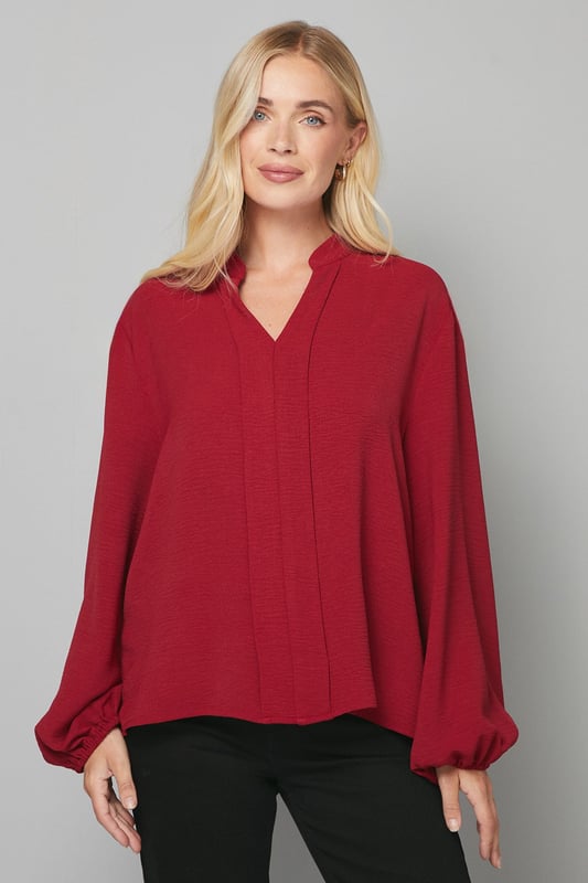 Elegant collarless design with a flattering V-neckline
        Relaxed silhouette with full-length sleeves for sophisticated comfort
        Lightweight woven fabric that drapes beautifully
        Versatile blouse perfect for creating both casual and smart looks
        Petite fit designed specifically for smaller frames
    
    This Wallis collarless blouse combines effortless style with day-to-day versatility. The clean lines and absence of a traditional collar create a modern, streamlined look that's both sophisticated and relaxed. Style with leather-look trousers and ankle boots for a contemporary daytime ensemble, or pair with tailored wide-leg trousers and ballet flats for family gatherings. The flowing fabric and comfortable regular fit make this blouse ideal for long days at the office or weekend brunches with friends. Add a structured tote and simple gold-toned jewellery to complete your look. This wardrobe essential transitions seamlessly from desk to dinner, offering endless styling possibilities whilst maintaining that signature Wallis glamour that doesn't compromise on comfort.