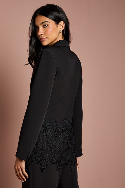 Tailored crepe blazer with elegant lace trim detailing along the hemline
        Sophisticated V-neckline with single-breasted button fastening
        Fitted silhouette that accentuates the waistline for a flattering shape
        Long sleeves with subtle structured shoulders for a refined look
        Versatile design suitable for formal occasions and evening events
    
    This exquisite Coast blazer combines timeless tailoring with delicate lace detailing for a contemporary twist on occasion wear. The fitted silhouette creates a beautifully feminine shape, whilst the crepe fabric offers structure with comfortable movement. Style with the matching trousers as seen for a sophisticated coordinated ensemble, or pair with a sleek midi skirt for an alternative take on formal dressing. Perfect for weddings and race day events, this blazer can be dressed up with statement earrings and a clutch bag. For evening occasions, layer over a silk camisole with tailored trousers and strappy heels. The versatile design ensures this piece will become a cornerstone of your occasion wardrobe, offering endless styling possibilities whilst maintaining an air of understated elegance.