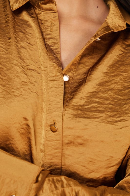 Distinctive hammered satin texture creates a luxe, tactile finish
        Oversized silhouette with dropped shoulders for effortless drape
        Classic collar and button-through front for versatile styling options
        Wide, relaxed sleeves with buttoned cuffs for added comfort
        Generous length perfect for layering or wearing as a standalone piece
    
    This Warehouse hammered satin shirt redefines casual sophistication with its sumptuous texture and relaxed fit. The oversized design creates a contemporary silhouette that's both comfortable and fashion-forward, whilst the lustrous finish adds a touch of understated glamour to everyday ensembles. Style it half-tucked into wide-leg trousers as shown for a coordinated look that transitions seamlessly from day to evening. For casual outings, pair with your favourite denim and trainers, or dress it up with tailored trousers and statement jewellery for dinner dates. The versatile nature of this piece makes it ideal for layering during cooler months or wearing alone when temperatures rise. Machine washable and crafted from cotton, this shirt combines practicality with Warehouse's signature confident, feminine aesthetic.
