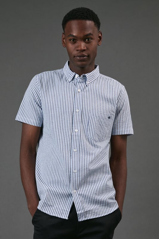 Classic button-down collar for a smart-casual finish
        Distinctive seersucker fabric with textured multi-stripe pattern
        Practical chest pocket with Maine brand detailing
        Short sleeves with neat hems for warm-weather comfort
        Box pleat at back for enhanced movement and fit
    
    This Maine seersucker shirt combines timeless style with practical warm-weather design. The textured multi-stripe pattern creates visual interest while the lightweight woven fabric offers breathability perfect for summer days. Style with dark chinos and white trainers for a relaxed weekend look, as shown, or pair with tailored shorts and loafers for garden parties and casual gatherings. The versatile button-down design transitions effortlessly from daytime outings to evening barbecues. For a layered approach, wear unbuttoned over a plain t-shirt with rolled sleeves. The classic fit provides comfortable movement without sacrificing style, making this shirt an essential addition to your casual wardrobe that will serve you well through numerous summer seasons.