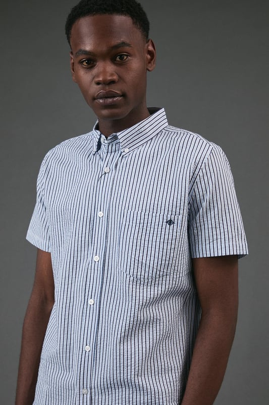 Classic button-down collar for a smart-casual finish
        Distinctive seersucker fabric with textured multi-stripe pattern
        Practical chest pocket with Maine brand detailing
        Short sleeves with neat hems for warm-weather comfort
        Box pleat at back for enhanced movement and fit
    
    This Maine seersucker shirt combines timeless style with practical warm-weather design. The textured multi-stripe pattern creates visual interest while the lightweight woven fabric offers breathability perfect for summer days. Style with dark chinos and white trainers for a relaxed weekend look, as shown, or pair with tailored shorts and loafers for garden parties and casual gatherings. The versatile button-down design transitions effortlessly from daytime outings to evening barbecues. For a layered approach, wear unbuttoned over a plain t-shirt with rolled sleeves. The classic fit provides comfortable movement without sacrificing style, making this shirt an essential addition to your casual wardrobe that will serve you well through numerous summer seasons.