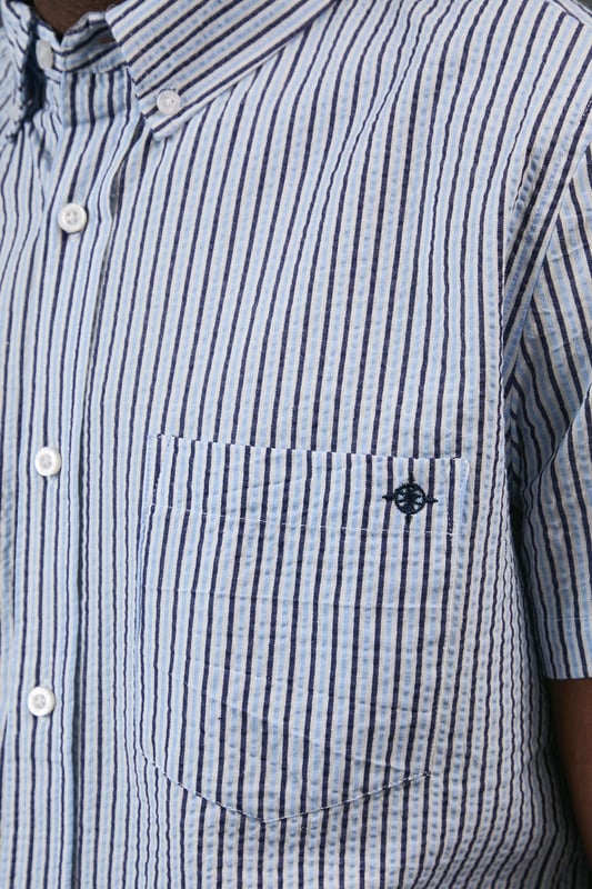 Classic button-down collar for a smart-casual finish
        Distinctive seersucker fabric with textured multi-stripe pattern
        Practical chest pocket with Maine brand detailing
        Short sleeves with neat hems for warm-weather comfort
        Box pleat at back for enhanced movement and fit
    
    This Maine seersucker shirt combines timeless style with practical warm-weather design. The textured multi-stripe pattern creates visual interest while the lightweight woven fabric offers breathability perfect for summer days. Style with dark chinos and white trainers for a relaxed weekend look, as shown, or pair with tailored shorts and loafers for garden parties and casual gatherings. The versatile button-down design transitions effortlessly from daytime outings to evening barbecues. For a layered approach, wear unbuttoned over a plain t-shirt with rolled sleeves. The classic fit provides comfortable movement without sacrificing style, making this shirt an essential addition to your casual wardrobe that will serve you well through numerous summer seasons.
