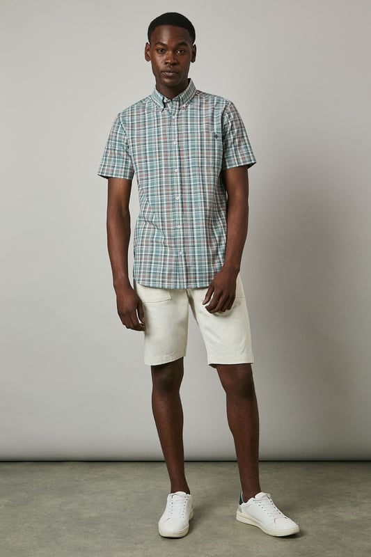 Classic button-down collar for a refined casual look
        Short sleeves with neat hems perfect for warmer weather
        Traditional check pattern adds visual interest and versatility
        Chest pocket with subtle Maine brand detailing
        Regular fit with back pleat for enhanced comfort and movement
    
    This Maine short sleeve shirt showcases a timeless check pattern that brings a touch of sophistication to your summer wardrobe. The button-down collar maintains structure while keeping things casual, making it ideal for various daytime occasions. As seen on our model, pair this versatile shirt with light-coloured shorts and white trainers for an effortlessly stylish weekend look. The shirt works brilliantly for family barbecues, casual garden parties, or relaxed pub lunches with friends. For a smarter appearance, tuck it into chino trousers and add a canvas belt. The breathable fabric ensures comfort during warmer days, while the classic pattern ensures this piece will remain a staple in your collection for seasons to come. Perfect for packing on weekend getaways or summer holidays when you need an easy-to-style option that delivers on both comfort and style.