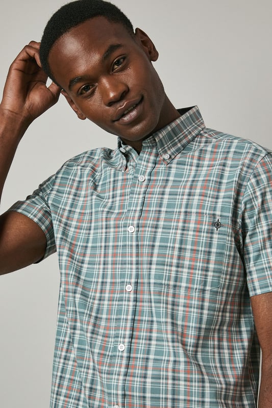 Classic button-down collar for a refined casual look
        Short sleeves with neat hems perfect for warmer weather
        Traditional check pattern adds visual interest and versatility
        Chest pocket with subtle Maine brand detailing
        Regular fit with back pleat for enhanced comfort and movement
    
    This Maine short sleeve shirt showcases a timeless check pattern that brings a touch of sophistication to your summer wardrobe. The button-down collar maintains structure while keeping things casual, making it ideal for various daytime occasions. As seen on our model, pair this versatile shirt with light-coloured shorts and white trainers for an effortlessly stylish weekend look. The shirt works brilliantly for family barbecues, casual garden parties, or relaxed pub lunches with friends. For a smarter appearance, tuck it into chino trousers and add a canvas belt. The breathable fabric ensures comfort during warmer days, while the classic pattern ensures this piece will remain a staple in your collection for seasons to come. Perfect for packing on weekend getaways or summer holidays when you need an easy-to-style option that delivers on both comfort and style.