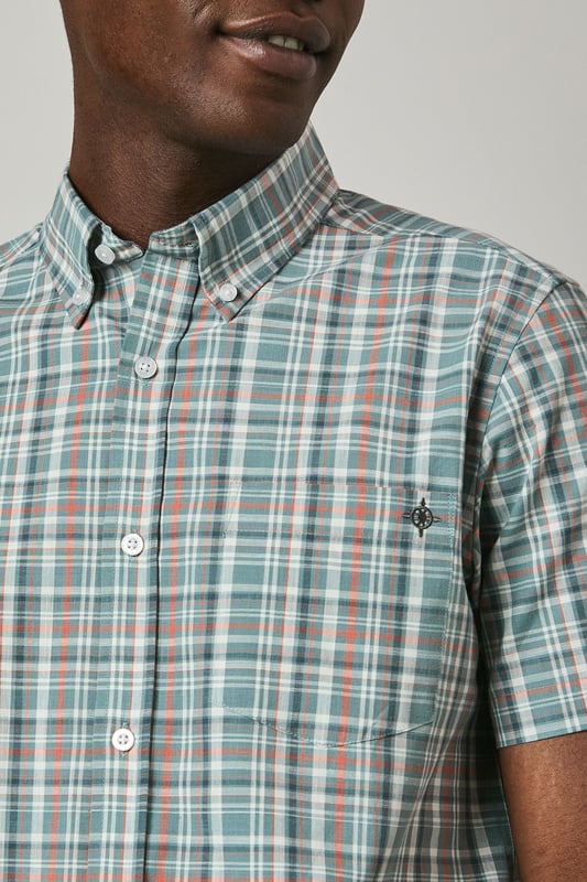 Classic button-down collar for a refined casual look
        Short sleeves with neat hems perfect for warmer weather
        Traditional check pattern adds visual interest and versatility
        Chest pocket with subtle Maine brand detailing
        Regular fit with back pleat for enhanced comfort and movement
    
    This Maine short sleeve shirt showcases a timeless check pattern that brings a touch of sophistication to your summer wardrobe. The button-down collar maintains structure while keeping things casual, making it ideal for various daytime occasions. As seen on our model, pair this versatile shirt with light-coloured shorts and white trainers for an effortlessly stylish weekend look. The shirt works brilliantly for family barbecues, casual garden parties, or relaxed pub lunches with friends. For a smarter appearance, tuck it into chino trousers and add a canvas belt. The breathable fabric ensures comfort during warmer days, while the classic pattern ensures this piece will remain a staple in your collection for seasons to come. Perfect for packing on weekend getaways or summer holidays when you need an easy-to-style option that delivers on both comfort and style.