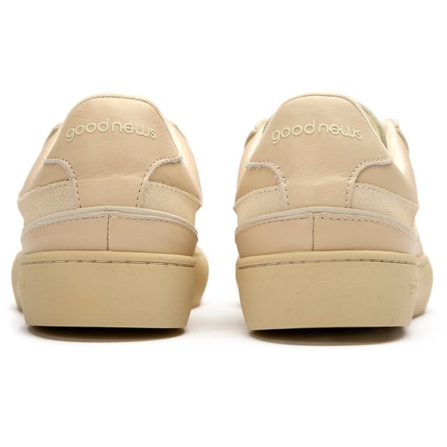 The Good News Lagoon trainers blend retro court styling with eco-conscious craftsmanship. These sand-colored kicks showcase handmade deadstock suede uppers with a distinctive stamped GN motif that adds subtle branding. The chunky organic cotton laces provide a textural contrast against the soft suede, while recycled mesh lining ensures breathable comfort. Perfect for the environmentally mindful gentleman seeking casual footwear with substance, these rubber-soled trainers deliver on both sustainability and laid-back style.