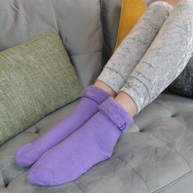 THMO Ladies Thermal Turnover Bed Socks: Embrace the cosy comfort of our THMO Bed Socks, your perfect pair for those chilly winter days and nights. As the temperature drops, it's essential to keep yourself warm while also saving on heating bills. Treat yourself to the ultimate warmth without compromising your budget. Crafted using a specially selected heavy bulk acrylic yarn, these socks possess exceptional thermal qualities that will keep your feet cosy even in the coldest of winters. To enhance their insulating properties, the socks have been double brushed on the inside, creating a plush and velvety texture that maximises warmth and provides softness against your skin. By effectively trapping warm air and enveloping your feet in comfort, these bed socks are the perfect choice for those moments of indoor relaxation and tranquillity. . An innovative anti-slip grip has been designed onto the foot of the sock in order to prevent you from slipping on surfaces such as hard wooden floors or kitchen tiles. . These THMO thermal bed socks are available in 3 colours: Purple, Pink & Blue, with dotted grippers. They are available in one size Ladies 4-8 UK. They are made from 93% Acrylic, 6% Polyamide & 1% Elastane. They are also safely machine washable. Extra Product Details: THMO Slipper Bed Socks Double Brushed Inner Thick & Warm Hand Linked Toe Turnover Top 3 Colour Options