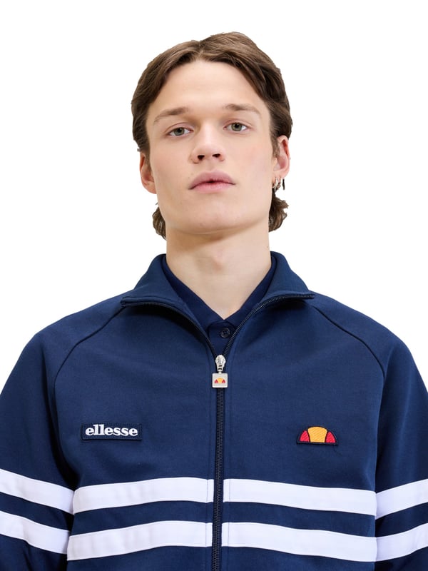 Diese Herren-Trainingsjacke verbindet sportliche Dynamik mit modernem Design. Der Color-Block-Look sorgt für einen frischen, markanten Auftritt. Raglanärmel bieten optimale Bewegungsfreiheit und betonen den lässigen Stil. Der Stehkragen setzt ein modisches Statement. Mit dem durchgehenden Reißverschluss lässt sich die Jacke schnell an- und ausziehen. Seitliche Eingrifftaschen bieten Platz für Kleinigkeiten oder einfach einen lässigen Griff. Bündchen an Ärmeln und Saum sorgen für einen perfekten Sitz. Dezente Label-Details runden das Design stimmig ab. Das weiche Material garantiert dabei besten Tragekomfort – den ganzen Tag. Ideal für sportive Outfits oder als cooler Alltagsbegleiter.