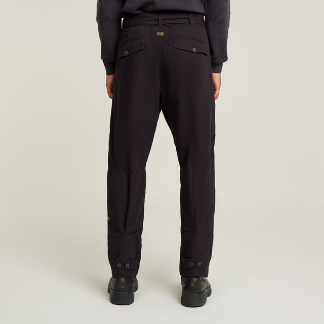 Zip fly. Side seam pockets, patched-on waist pockets. Flap pockets at the back, snap buttons. Belt. Adjustable leg width, tab. Button & zip closure. Mid waist. This Fatigue pant is designed in a relaxed tapered fit. The pleats at the side and the tabs at the ankle add to it. These pants combine side seam pockets with pockets at the front. The backside shows flap pockets with a snap button closure. Use the belt to finetune the fit. 100% Cotton. Rigid. Tapered