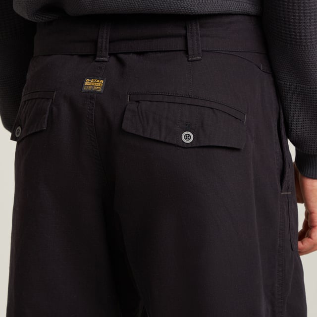 Zip fly. Side seam pockets, patched-on waist pockets. Flap pockets at the back, snap buttons. Belt. Adjustable leg width, tab. Button & zip closure. Mid waist. This Fatigue pant is designed in a relaxed tapered fit. The pleats at the side and the tabs at the ankle add to it. These pants combine side seam pockets with pockets at the front. The backside shows flap pockets with a snap button closure. Use the belt to finetune the fit. 100% Cotton. Rigid. Tapered